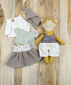 three stuffed animals laying on top of a wooden floor next to clothes and shoes for dolls