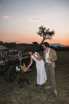 a man and woman standing next to each other in front of a truck at sunset