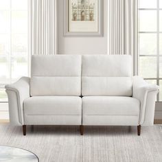 a white couch sitting in front of a window on top of a carpeted floor