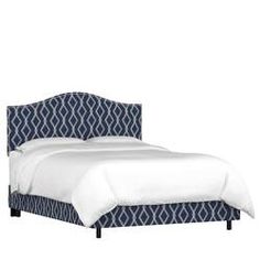 an upholstered bed with white sheets and blue patterned headboard is shown against a white backdrop