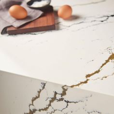 some eggs are sitting on top of a marble counter with gold veining and black accents