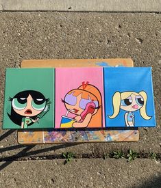 three paintings of cartoon characters are on a bench in front of a sidewalk with grass