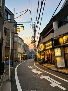 an empty street with people walking on the side walk at sunset or dawn in japan