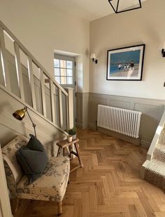 a living room with wooden floors and white walls, along with a staircase leading up to the second floor