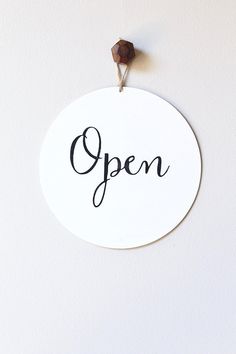 an open sign hanging on the wall next to a piece of wood and a wooden bead