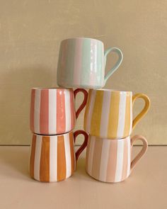 three striped mugs are stacked on top of each other