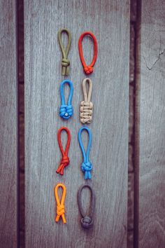 four different colored ropes are laid out on a wooden surface, with one knot in the middle