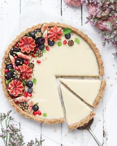 a cheesecake with fruit and flowers on it is cut in half to show the pie's filling