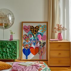 a bedroom with a bed, dresser and art work on the wall in front of it