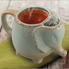 an elephant shaped tea cup sitting on top of a green napkin