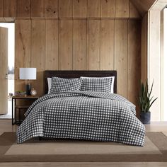 a black and white checkered comforter on a bed in a room with wood paneling