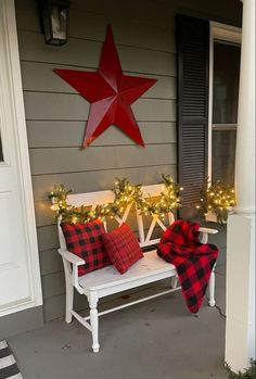 a white bench sitting on top of a porch next to a christmas wreath and lights