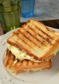 a grilled cheese sandwich on a plate with a glass of water in the background