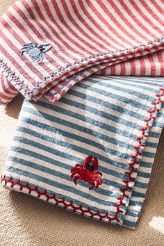 two red and white striped shirts with crab appliques on the front, one in blue