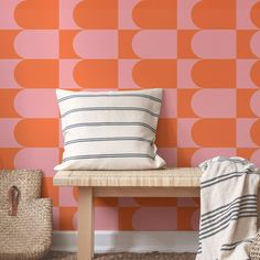 an orange and pink geometric wallpaper in a room with a bench next to it