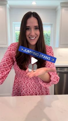 a woman is holding up a sign with the words jumping beans in front of her