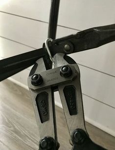 a pair of black and silver pliers on a wooden floor next to a white wall