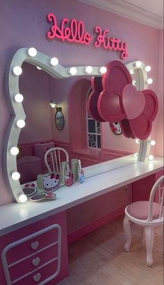 a hello kitty themed bedroom with pink furniture and lights on the mirror, vanity table and chair