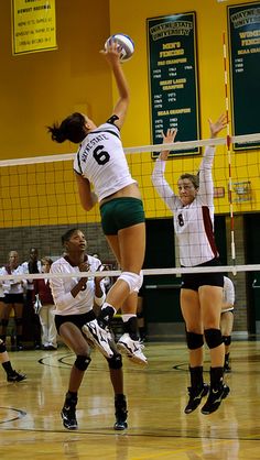 the volleyball players are jumping up to hit the ball