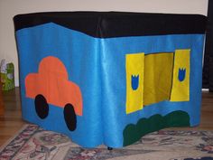 a child's play tent with cars on the front and sides, sitting on top of a rug