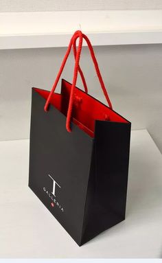 a black shopping bag with red handles sitting on a table