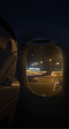 an airplane window looking out on the runway at night with lights in the sky and cars driving down the road