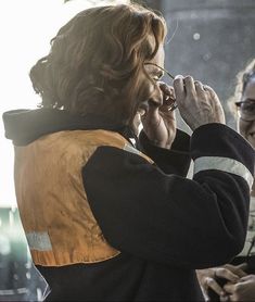 a woman is talking on her cell phone while another woman watches from the sidelines