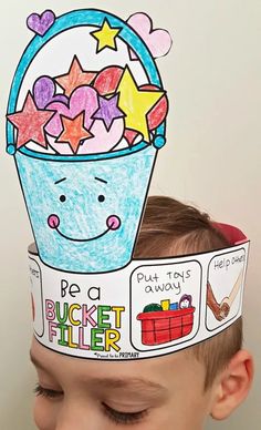 a young boy wearing a paper basket with stars on it's head and the words be a bucket filler above his head