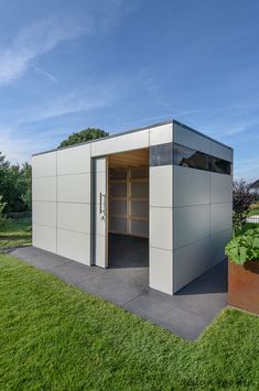 an outdoor storage shed with open doors on the side and green grass in the foreground