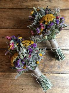 two bouquets of dried flowers sitting on top of a wooden floor