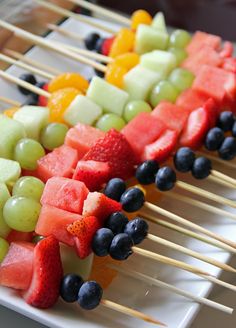 fruit skewers are arranged on a white plate