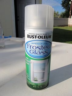 a can of frosted glass paint sitting on top of a white table outside with grass in the background