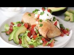 a white plate topped with an enchilada covered in lettuce and tomatoes