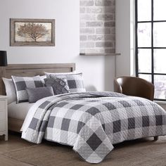 a black and white checkered comforter on a bed in a room with brick walls