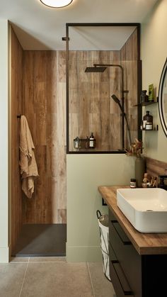 a bathroom with a sink, mirror and shower in it's center wall is made of wood