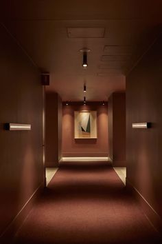 an empty hallway with red carpet and two lights on either side of the corridor wall