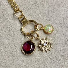 Created in 18 karat yellow gold Rhodolite garnet 3.50 carats approx. Opal 0.80 carat approx. Diamonds 0.10 carat approx. Limited edition Chain sold separately  Hand-crafted from 18 karat yellow gold, this limited-edition Three charms features a 3.50-carat Rhodolite garnet and a 0.80-carat opal, offset by 0.10 carats of diamonds. Chain sold separately.  About the Designers ~ Dharmesh & Namrata  Drawing inspiration from little things, Dharmesh & Namrata Kothari have created an extraordinary and refreshing collection of luxurious jewels. True believers of destiny, they always feel that the possibilities of design - and life - are limitless when people work together. Formed in 2003, Syna Jewels has grown through enduring relationships with well known, established companies and have evolved by Yellow Gold Jewelry With Gemstone Accents, Heirloom Gold Ruby Jewelry, Gold Gemstones Birthstone, Gold Tourmaline Jewelry For Anniversary, Gold Fusion Style Jewelry With Birthstone, Yellow Gold Ruby Jewelry With Gemstone, Heirloom Ruby Jewelry In Gold, Heirloom Gold Gemstones For Gift, Heirloom Gold Gemstones Gift