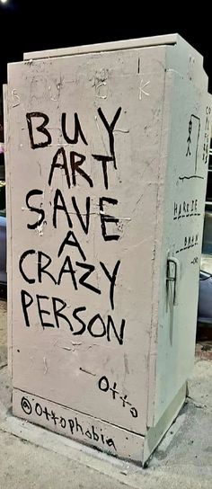 a white box with black writing on it sitting in front of a parking lot at night