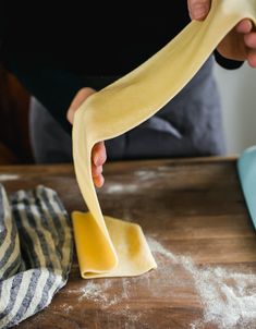 a person is kneading dough on top of a wooden table