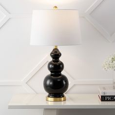 a black lamp sitting on top of a table next to a white vase with flowers