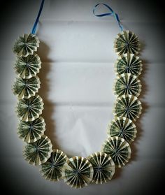 an origami necklace made out of dollar bills on a white background with blue ribbon