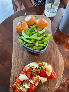 a wooden cutting board topped with food on top of a table