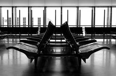 black and white photo of an airport terminal with empty benches in front of the windows