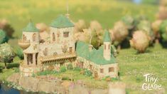 a miniature model of a castle in the middle of a field with trees and flowers