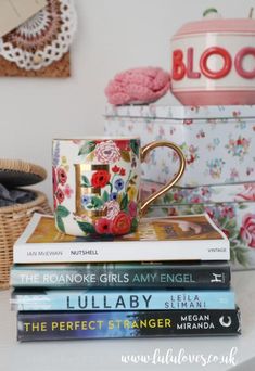 a stack of books sitting on top of a table next to a cup and saucer