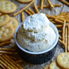 a bowl filled with cheese and crackers on top of a table next to crackers