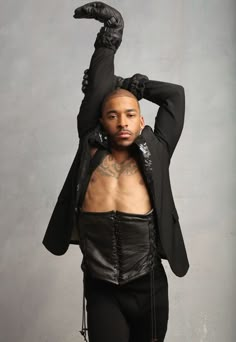 a man in black leather pants and jacket with his hands on his head, posing for the