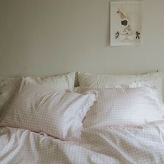 an unmade bed with white sheets and pink gingham pillow cases on it