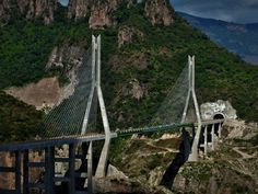 the bridge is high above the mountains and it looks like it's going over water