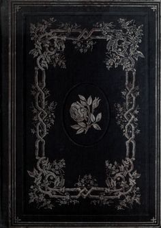 an old black book with white flowers and vines on the cover, sitting in front of a dark background